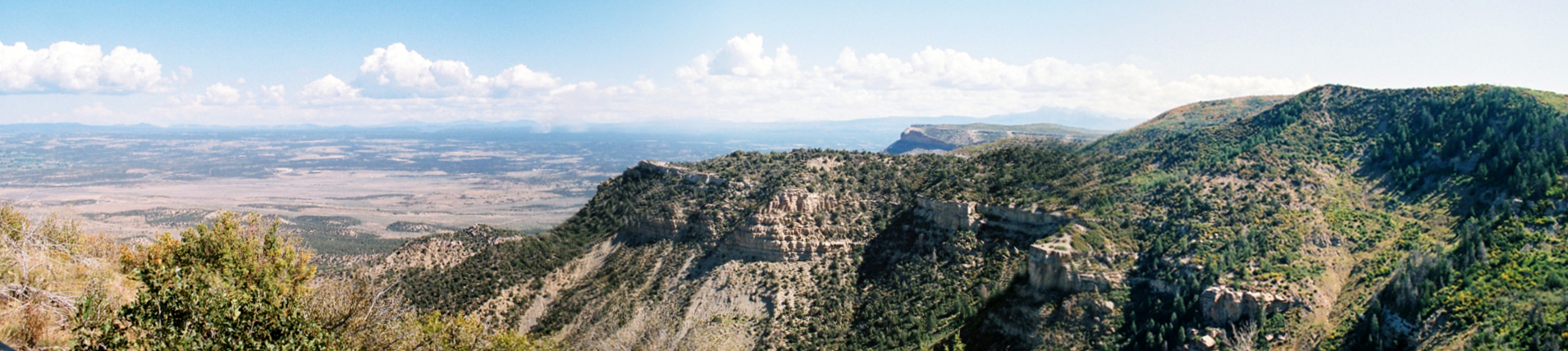 [Several photographs stitched together displaying a scenic view with mountains on the right and the valley floor way below on the left.]